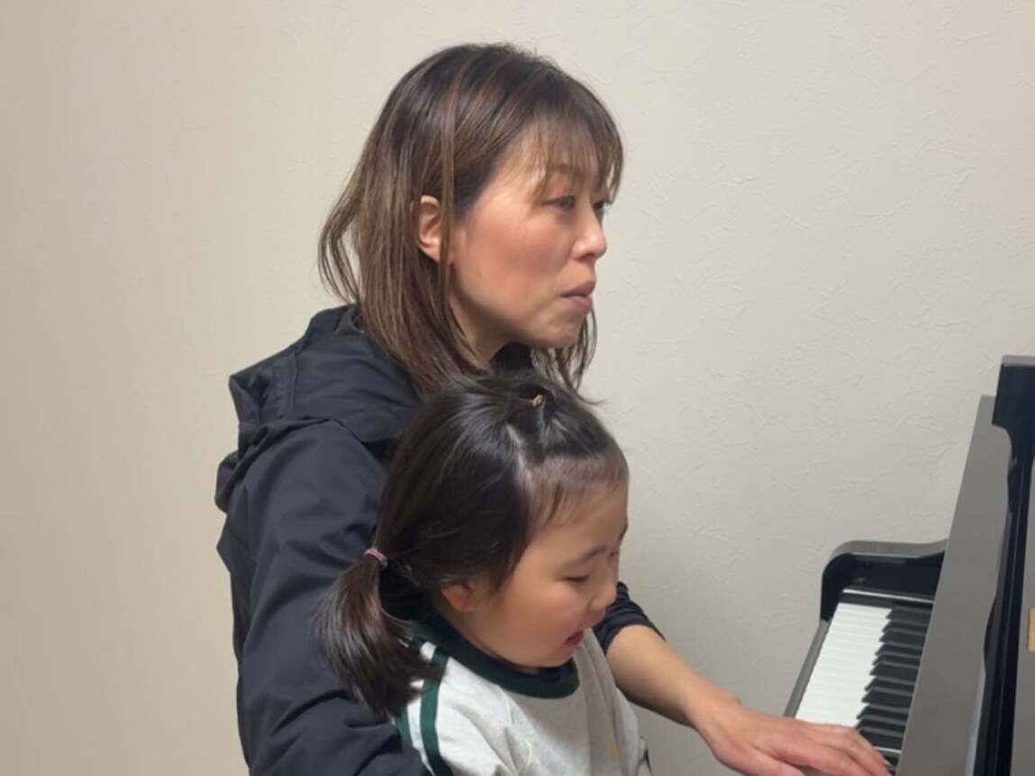 先生が寄り添いながら一緒に弾く様子